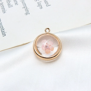 Vue macro d'un pendentif rond doré avec fleur séchée rose sur de la soie blanche