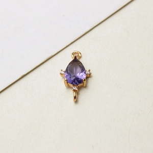 Makroaufnahme der vergoldeten Tropfenanhänger mit lila Zirkon und Doppelösen für DIY-Schmuck