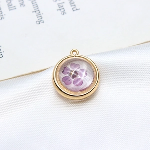 Vue macro d'un pendentif rond doré à l'or avec une véritable fleur séchée violette