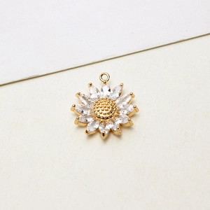 Macro dettaglio di un ciondolo a forma di girasole dorato con petali di zircone per DIY