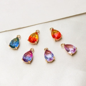 Macro shot of gold-plated teardrop glass pendants for DIY jewelry making on white silk