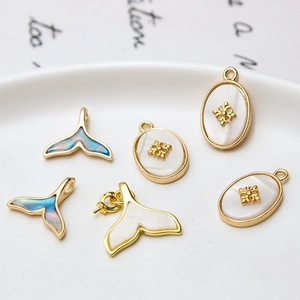 DIY jewelry charms featuring gold copper fish tail and shell-inlaid oval pendants