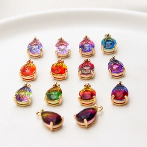 Macro shot of faceted pear-shaped glass charms with gold plated claw settings in a dish