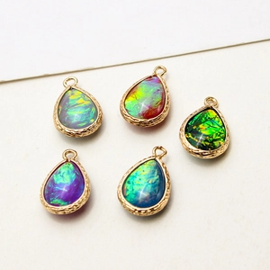 Five pieces of teardrop faux opal charms with gold plated borders and vintage textures