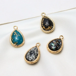 Detailed macro view of teardrop resin opal charms with gold-plated copper frames