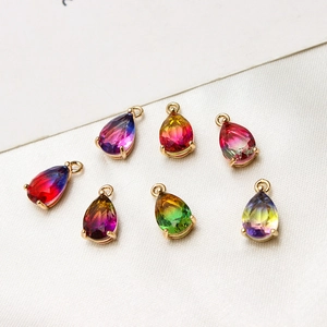 Macro detail of seven gradient teardrop crystal pendants on white silk fabric