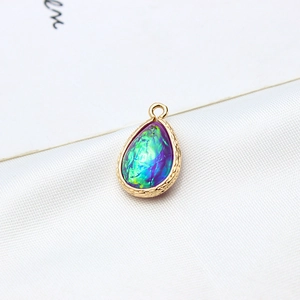 Detailed view of teardrop resin opal pendant with gold-plated copper edge on silk fabric
