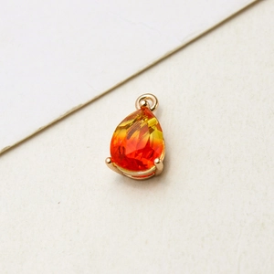 Detail of gradient teardrop pendant with gold-plated claw setting and faceted glass texture