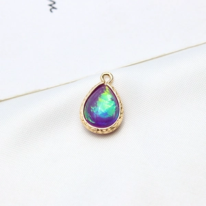 Macro detail of teardrop opal pendant with gold-plated frame on silk background