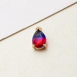 Macro shot of gradient pear-shaped glass pendant with gold-plated claw setting and loop