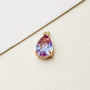 Macro detail of teardrop glass pendant with pink-blue gradient in gold plated setting