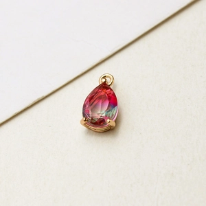Macro shot of gold-plated pear-cut glass drop pendant with pink to green gradient