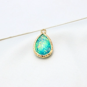Macro view of water drop opal pendant with gold plated edge and textured rim detail