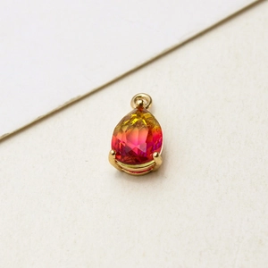 Macro shot of a yellow-red gradient glass teardrop pendant with gold-plated bezel setting