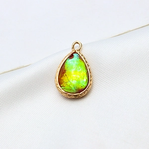 Macro shot of gold-plated teardrop resin opal pendant with intricate woven texture