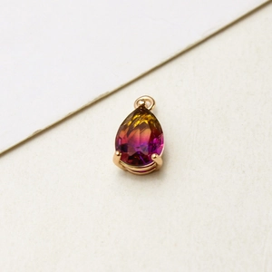 Macro shot of gold-plated pear-shaped crystal pendant with yellow to rose pink gradient effect