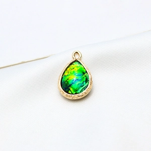 Detailed close-up of a gold-plated teardrop resin opal pendant with engraved edges