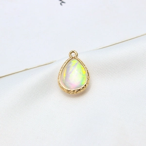 Macro shot of gold plated teardrop resin opal pendant with textured metallic borders