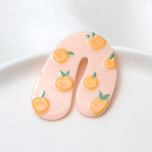 Detail of U-shaped acrylic earrings with orange patterns in a white ceramic bowl