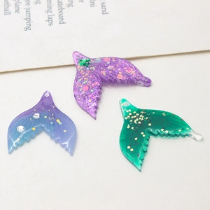 Macro detail of acrylic mermaid tail charms with colorful sequins for DIY jewelry making