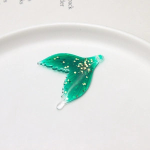 Detailed view of translucent green fish tail pendant with embedded gold sequins for DIY crafts