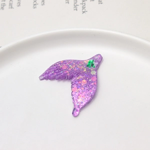 Macro shot of purple translucent acrylic mermaid tail pendant with colorful glitter sequins