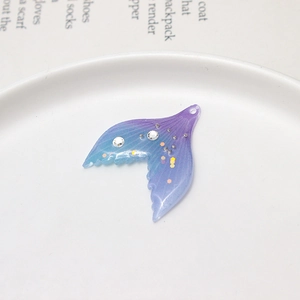 Macro shot of gradient mermaid tail charm with glitter sequins on a white dish