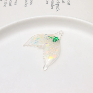 Detailed macro view of a resin butterfly wing charm with iridescent green sequins