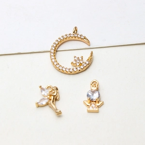 Macro shot of gold-plated celestial moon and angel pendants with sparkling zircon stones