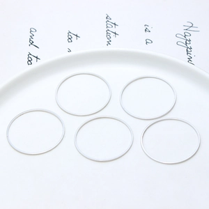 Detailansicht von fünf silbernen geometrischen Rundringen auf weißer Keramikschale für DIY
