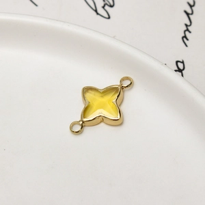 Detail of gold-plated four-leaf flower pendant with yellow crystal for DIY jewelry