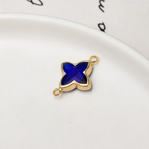 Close-up of blue glass four-pointed star pendant charm with gold-plated metal frame