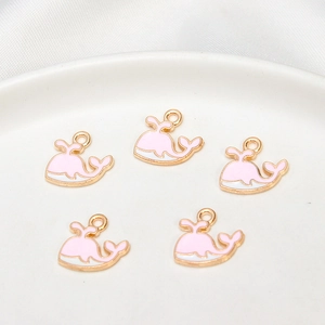 Detailed view of pink and white whale charms with gold edges for DIY jewelry making