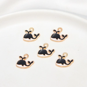 Macro view of five cute whale alloy charms with black and white enamel for DIY jewelry