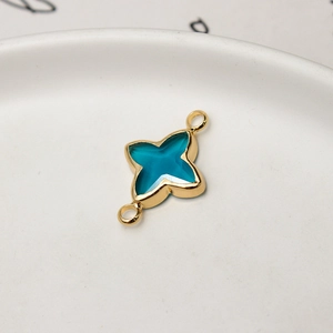 Macro shot of gold-plated clover jewelry connector with blue faceted gem for DIY crafting