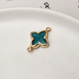 Macro view of gold-plated clover charm with deep cyan gemstone for DIY jewelry