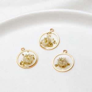 Detailed macro view of handmade resin flower charms with gold foil and white dry flower