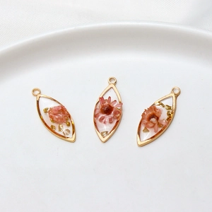 Macro view of gold-rimmed resin leaf pendants with dried flowers and gold foil details