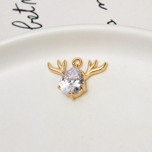 Close-up of golden reindeer pendant with cubic zirconia on white ceramic tray