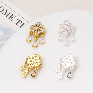 Gold and silver clover charms with zircon tassels displayed on a white ceramic tray