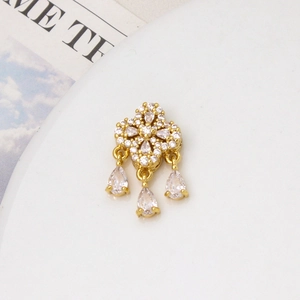 Macro detail of gold plated four-leaf flower charm with drop cubic zirconia tassels