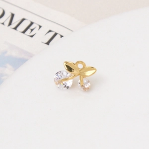 Macro shot of gold-plated cherry pendant with clear cubic zirconia stones and leaf detail