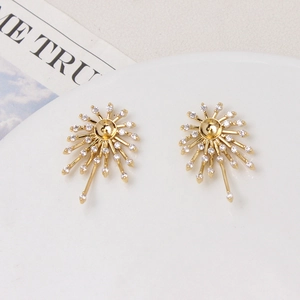 Vue détaillée des boucles d'oreilles feux d'artifice dorées avec zircon sur plateau blanc