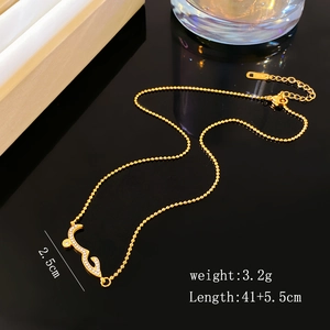 Detail of gold beaded necklace with zircon paved curved pendant and K18 metal tag