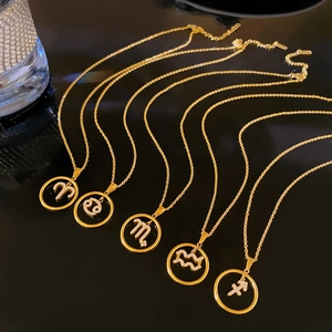 Detailed close-up of gold zodiac pendants with sparkling crystals on a dark reflective base