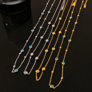 Gold and silver evil eye necklaces with polished metallic beads on reflective black background