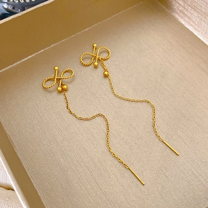 Dettaglio di orecchini a fiocco dorati con nappe su una scatola di gioielli raffinata