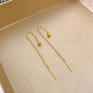 Dettaglio di orecchini a catenella dorati con sfere lucide e sottili fili metallici