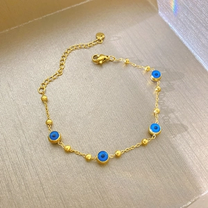 Bracelet chaîne dorée avec perles d'œil bleu et fermoir mousqueton au style minimaliste