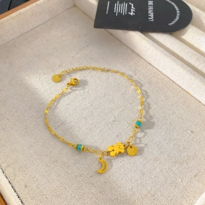 Macro detail of gold bear and moon charms with turquoise beads on a titanium chain